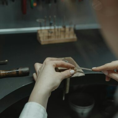 Close-up of a jeweler crafting jewelry on a workbench indoors.