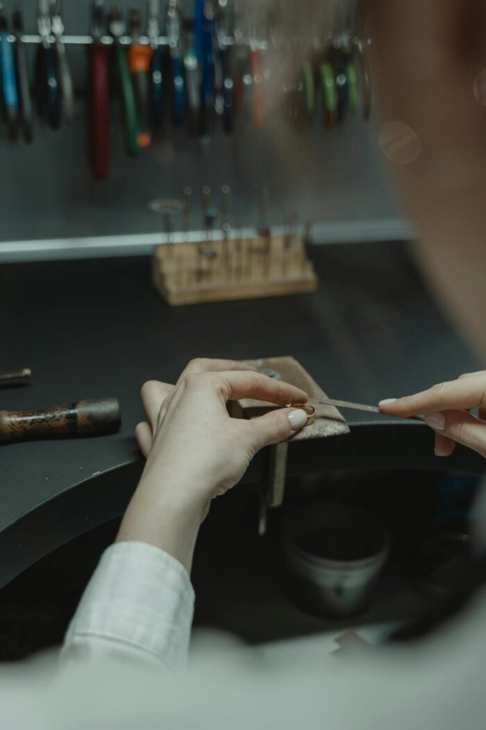 Close-up of a jeweler crafting jewelry on a workbench indoors.