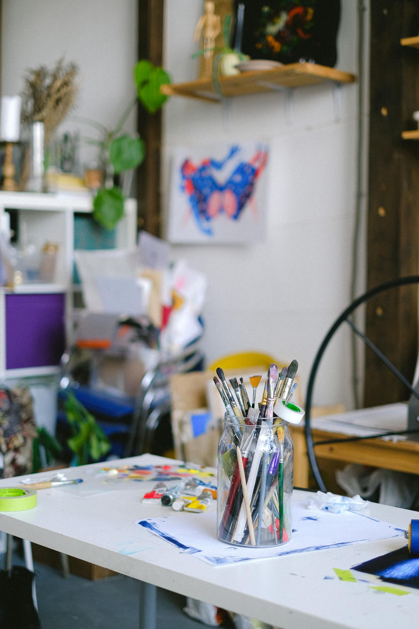 Colorful art studio workspace with paintbrushes and art supplies on a desk, inspiring creativity.