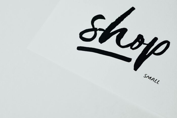 Elegant handwritten 'shop' sign on white background, perfect for retail design.